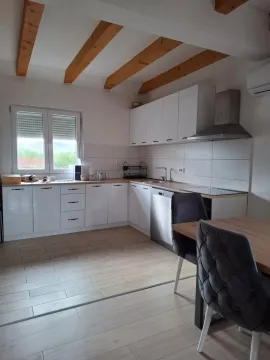 Moderna kuhinja sa bijelim elementima i drvenim gredama na plafonu. - image 13