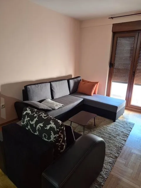 Living room with a sectional sofa, coffee table, and balcony doors.