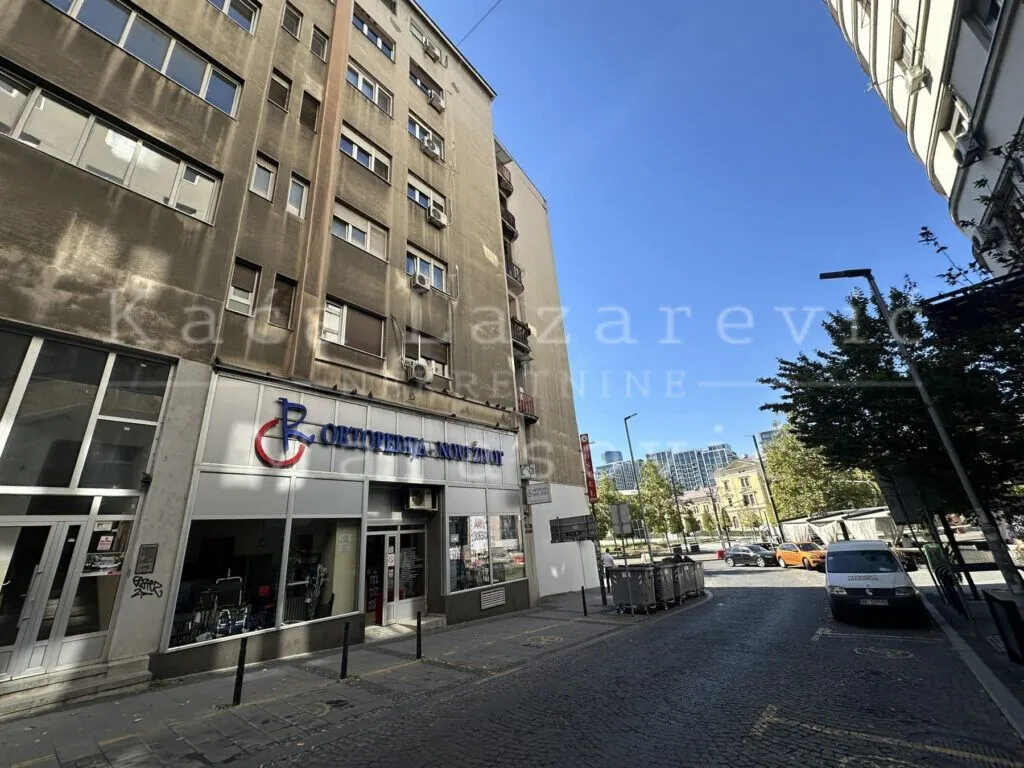 View of the street and the exterior of the building with commercial space on the ground floor.