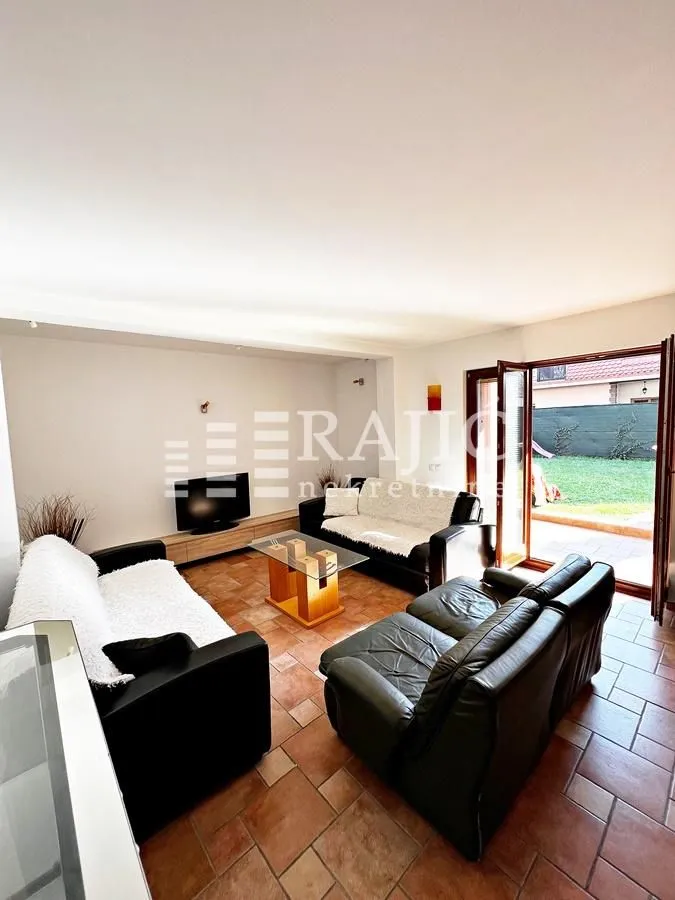 Spacious living room with seating furniture and exit to the yard.