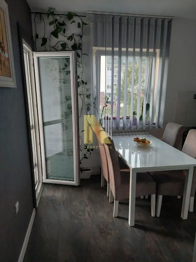 Trpezarija sa stolom, stolicama i izlazom na terasu.