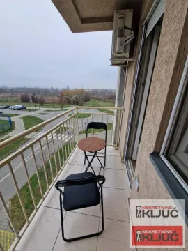 Nameštena terasa sa malim stolom i stolicama i pogledom na ulicu. - image 9