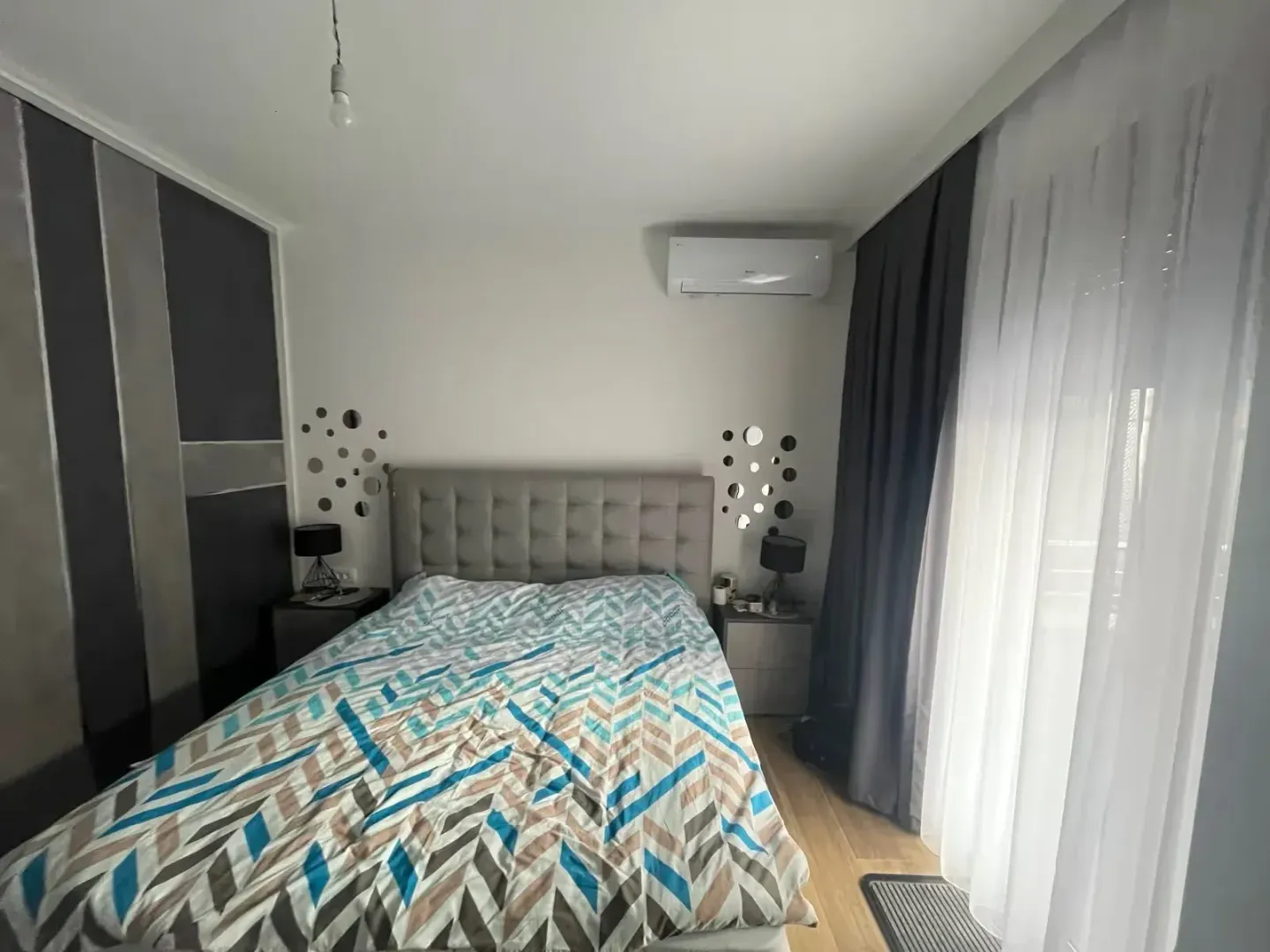 Furnished bedroom with a double bed, bedside tables, and a wardrobe.