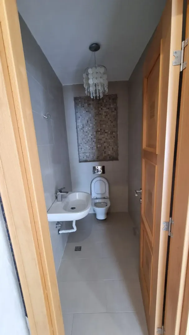 Pogled na kupatilo sa umivaonikom i wc šoljom kroz otvoren vrata.