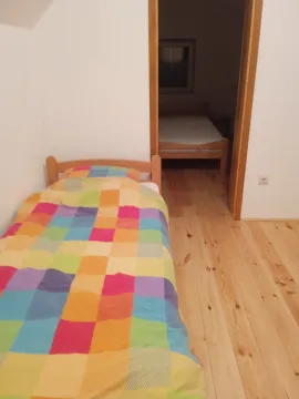 Jednostavna spavaća soba sa drvenim podom i jednim krevetom. - image 7