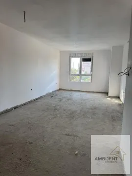 Prazna prostorija u neopremljenom stanju sa prozorom i grubim radovima na podu. - image 3