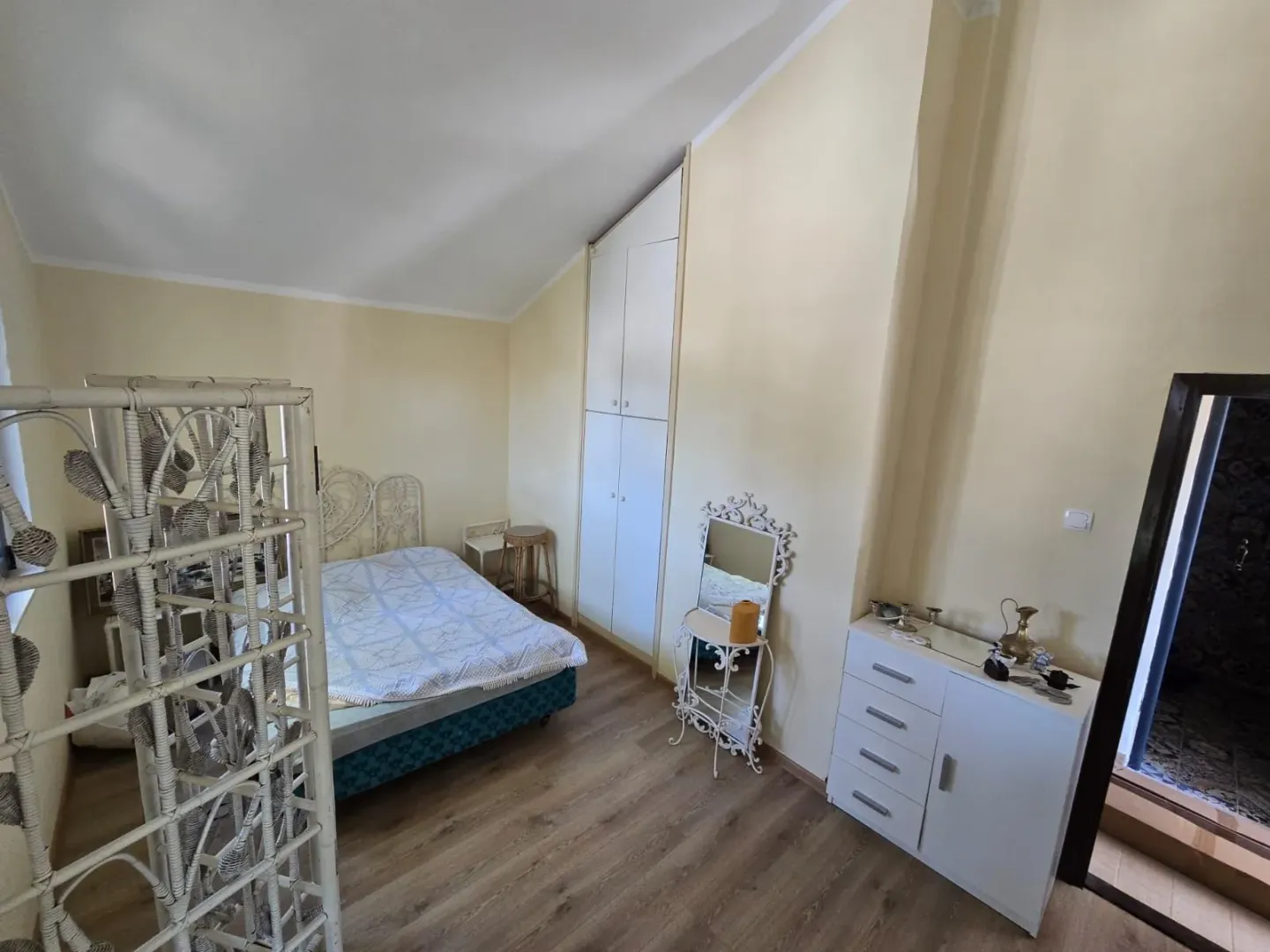 Namještena spavaća soba sa bračnim krevetom, ugradnim plakarom i komodom.