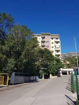 Pogled na stambenu zgradu sa okolnim drvećem i ulicom. - image 13