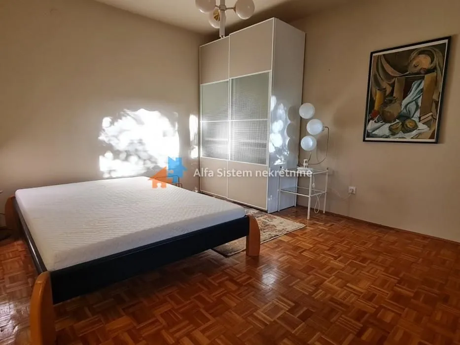Furnished bedroom with a double bed, wardrobe, and parquet flooring.