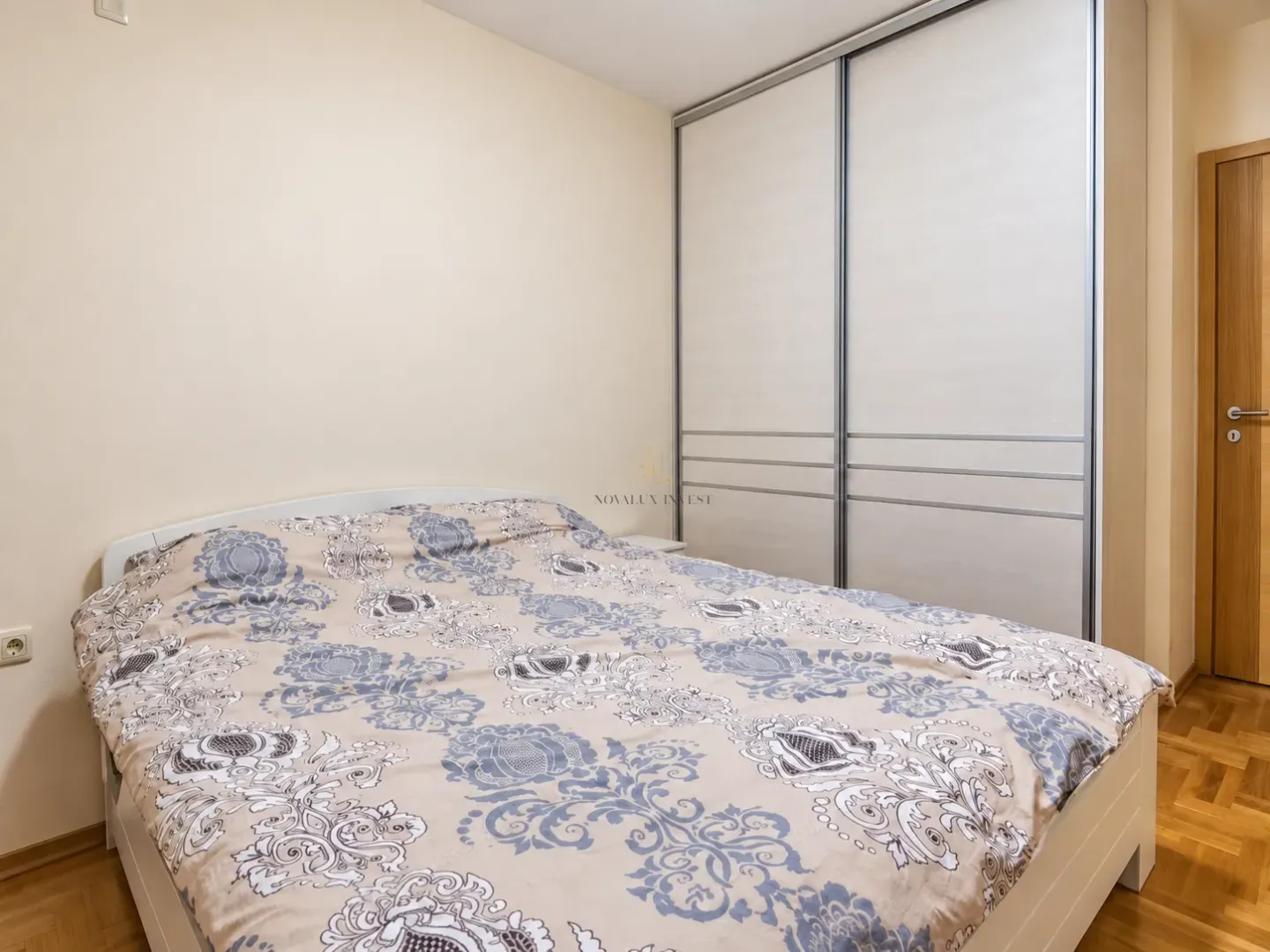Namještena spavaća soba sa bračnim krevetom i velikim ugradnim garderoberom.