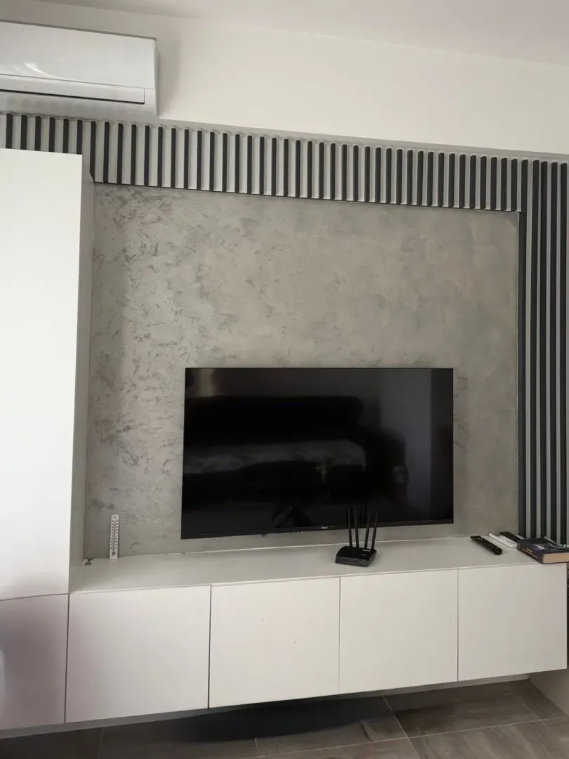 Living room with TV cabinet and decorative wall.
