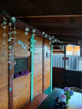 Natkrivena drvena terasa sa stolom i ukrasnim detaljima. - image 5