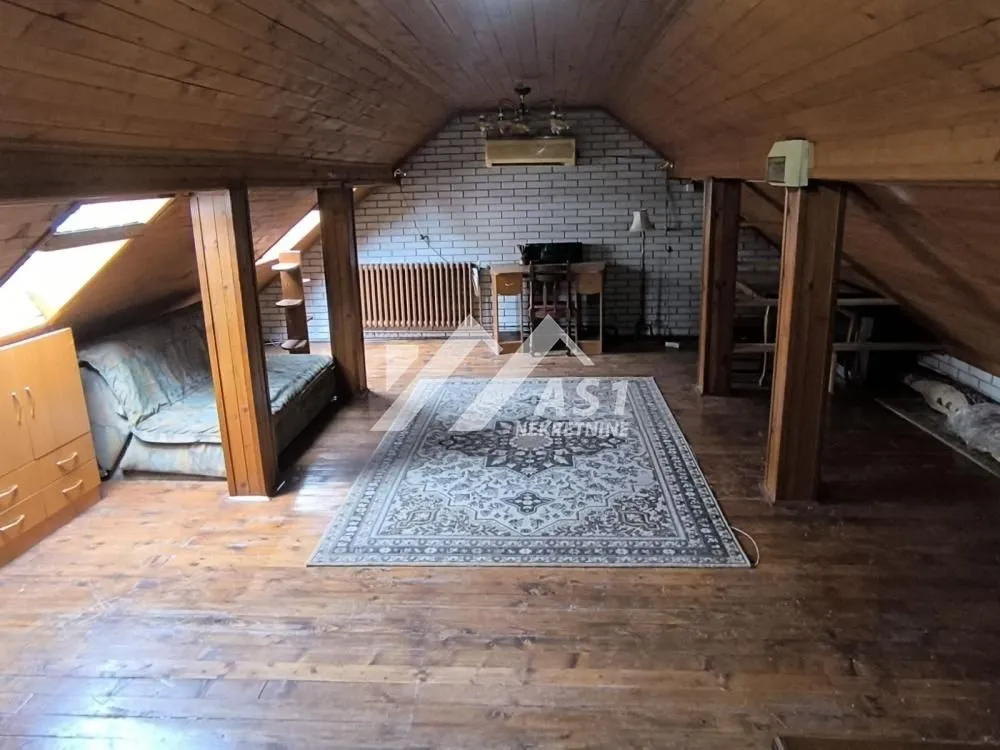 Attic space with wooden paneling on the ceiling and walls, furnished with a sofa and carpet.