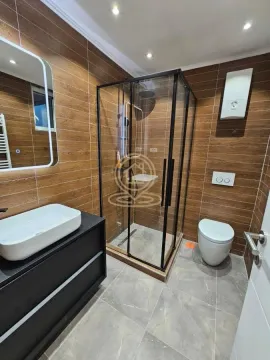 Modern bathroom equipped with a shower cabin, washbasin, and toilet. - image 4