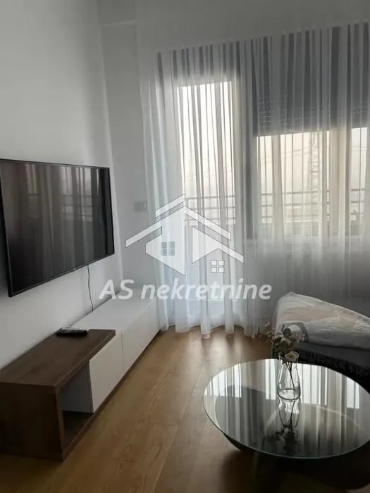 Living room with a TV, a low sideboard, and a glass coffee table.