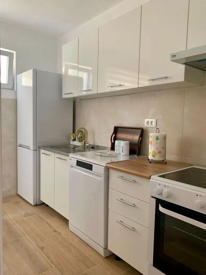 Bright and equipped kitchen with white cabinets.