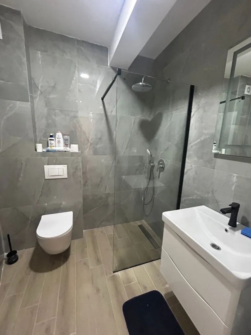 Modern bathroom equipped with a walk-in shower and grey tiles.