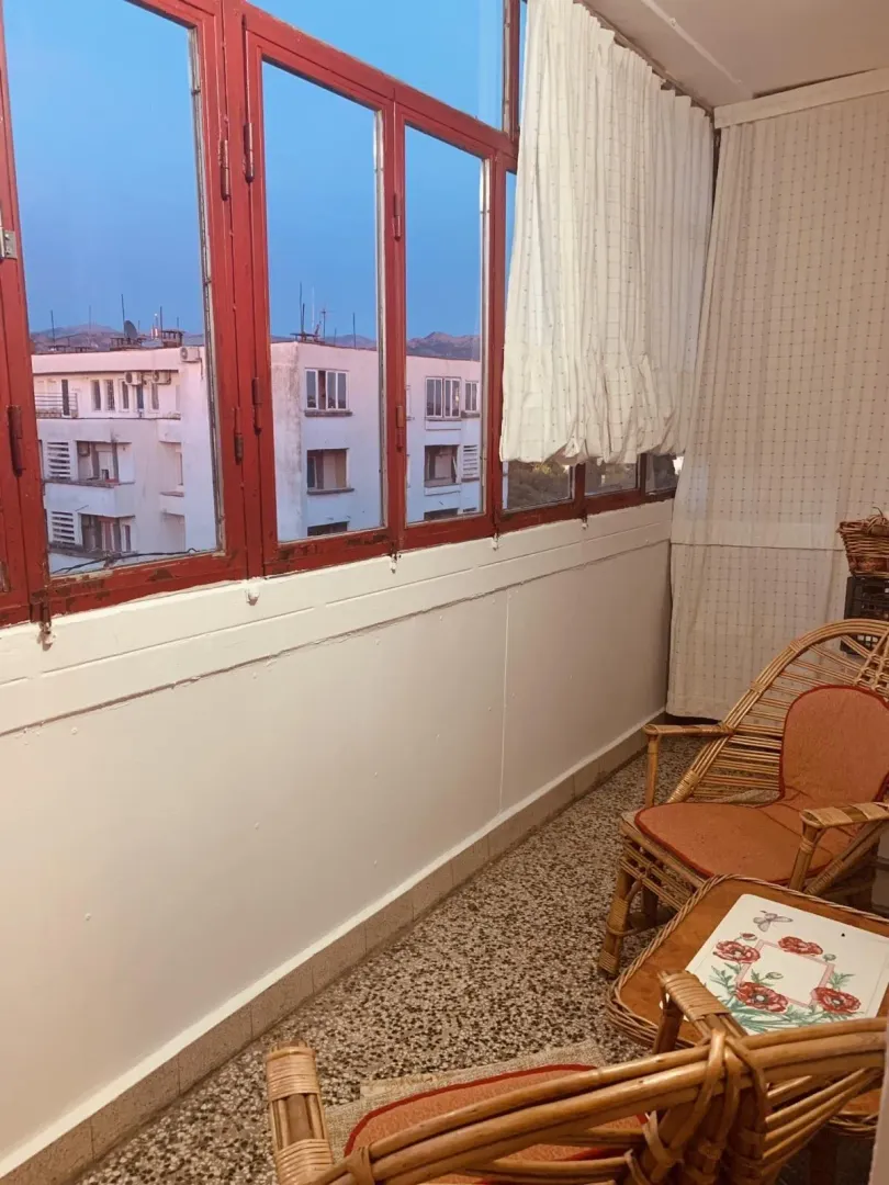 Enclosed balcony with wicker furniture.