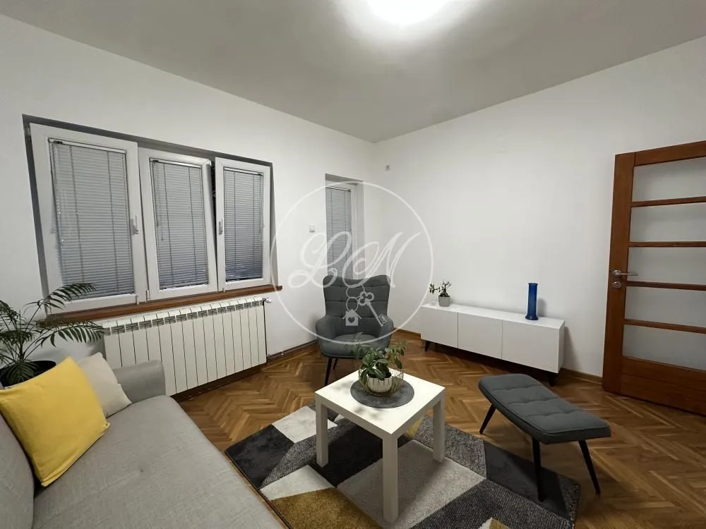 Living room with a sofa, coffee table, and windows with blinds.