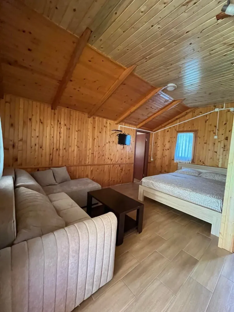 Dnevni boravak sa krevetom i drvenim oblogama na zidovima i plafonu.
