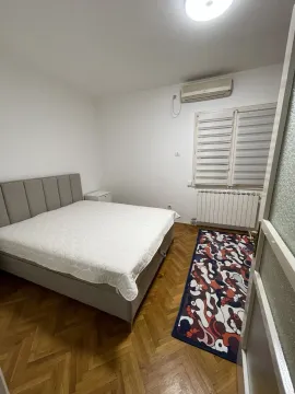 Svijetla spavaća soba sa bračnim krevetom, parketom i šarenim tepihom. - image 14