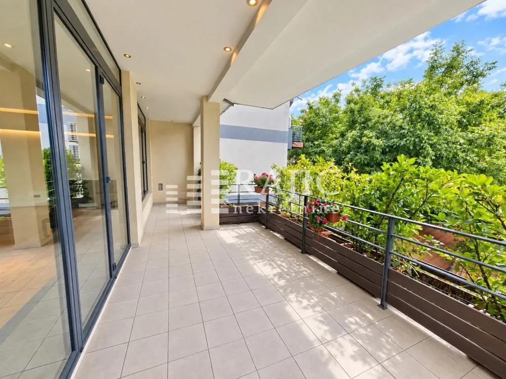 Spacious covered terrace with a view of greenery and surrounding buildings.