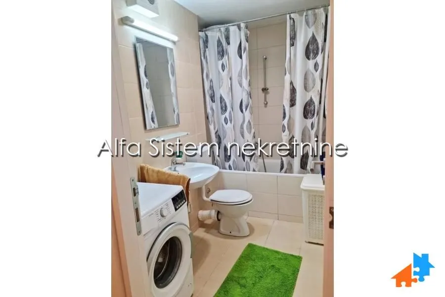 A compactly equipped bathroom with a bathtub, washbasin, and washing machine.