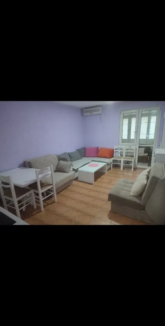 Living room with sofa set, dining table and balcony access.
