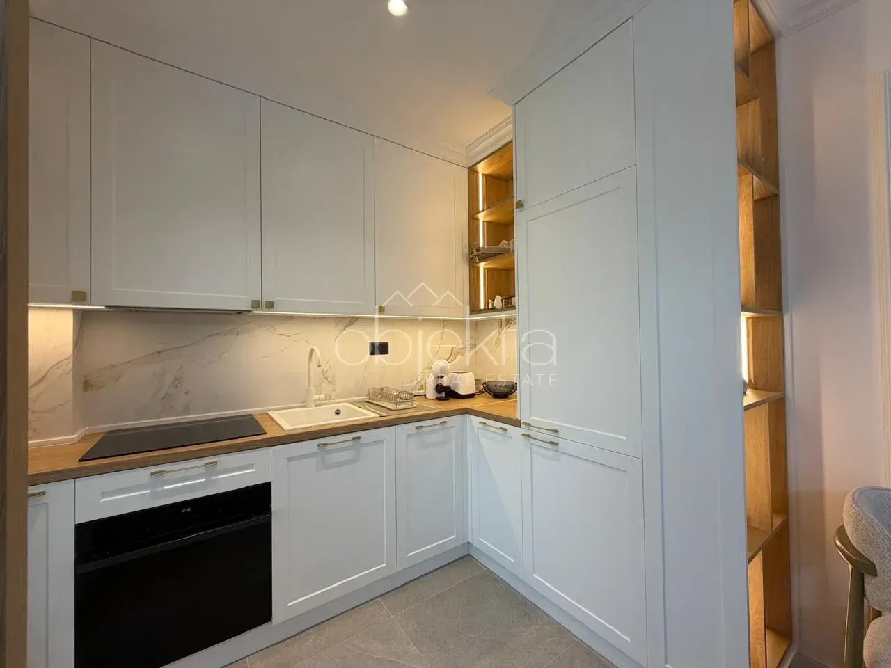 Modern white kitchen with wooden countertops and built-in appliances.