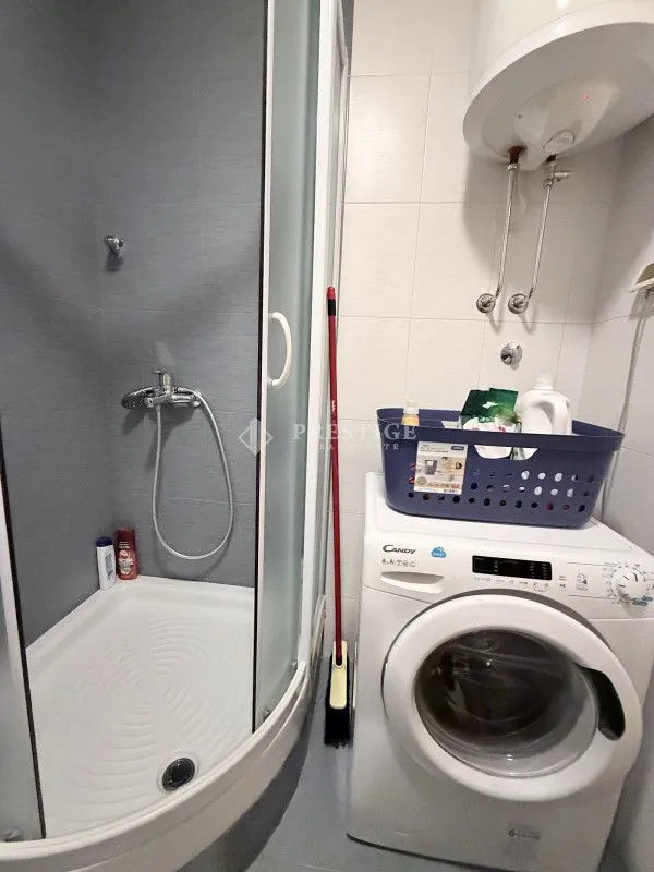 Manje kupatilo sa tuš kabinom, veš mašinom i bojlerom.