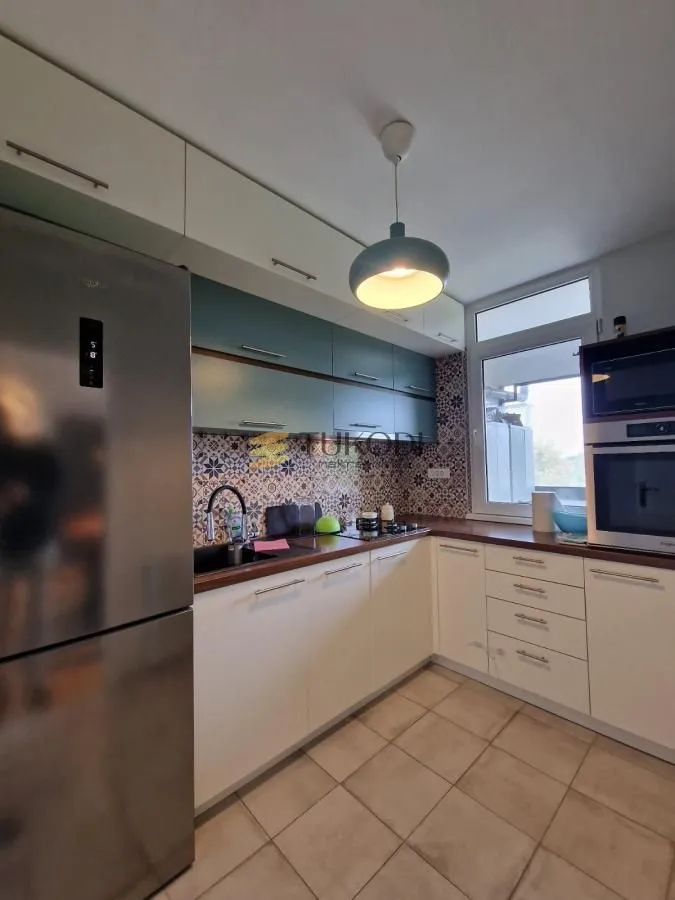 Small equipped kitchen with white and blue cabinets and built-in appliances.