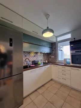 Small equipped kitchen with white and blue cabinets and built-in appliances. - image 10