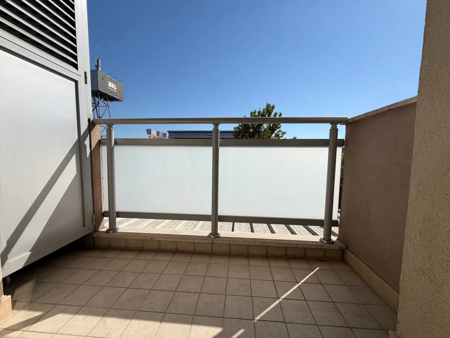 Smaller tiled terrace with metal railing and frosted glass.