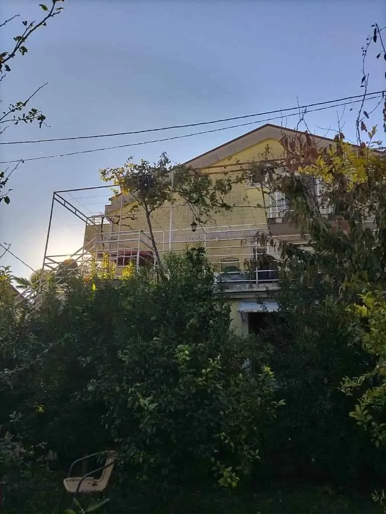 Vanjski izgled kuće sa dvorištem i zelenilom.