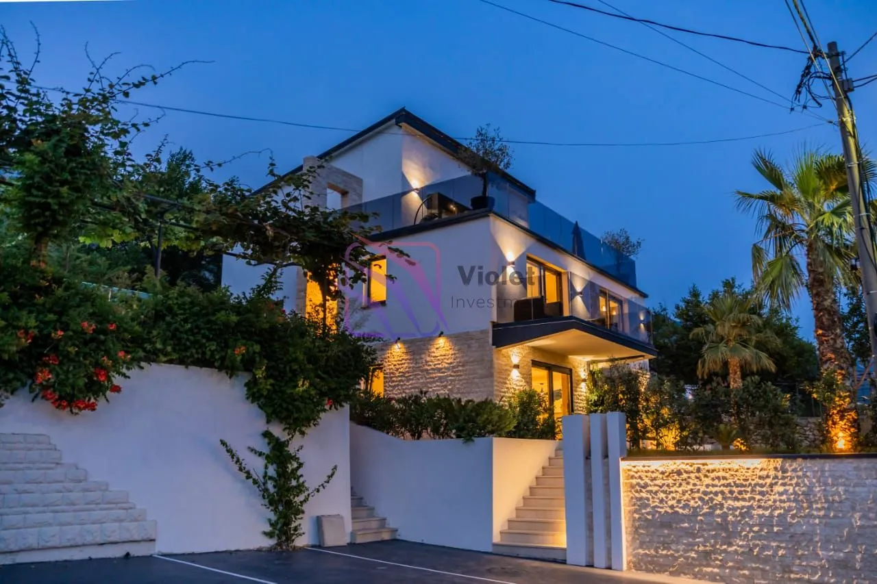 View of the illuminated house facade and yard at dusk.
