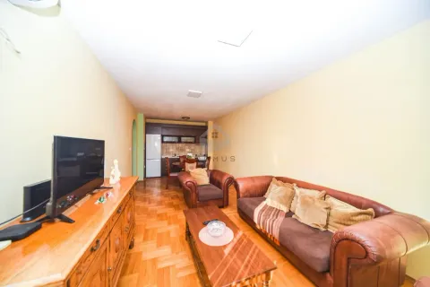 Living room with a sofa, TV cabinet, and dining area in the background. - image 4