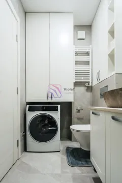 Moderno opremljeno kupatilo sa veš mašinom i bijelim ormarićima. - image 10