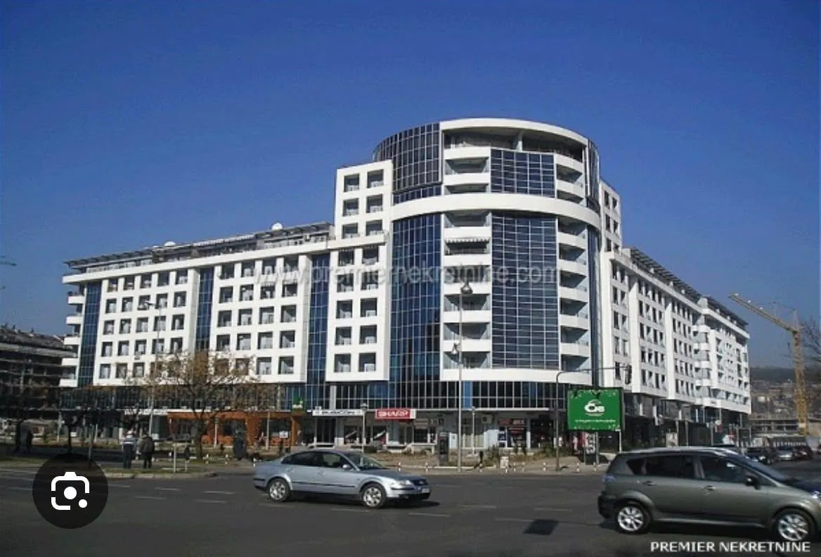 Pogled na modernu stambeno-poslovnu zgradu sa staklenom fasadom i ulicom u prvom planu.