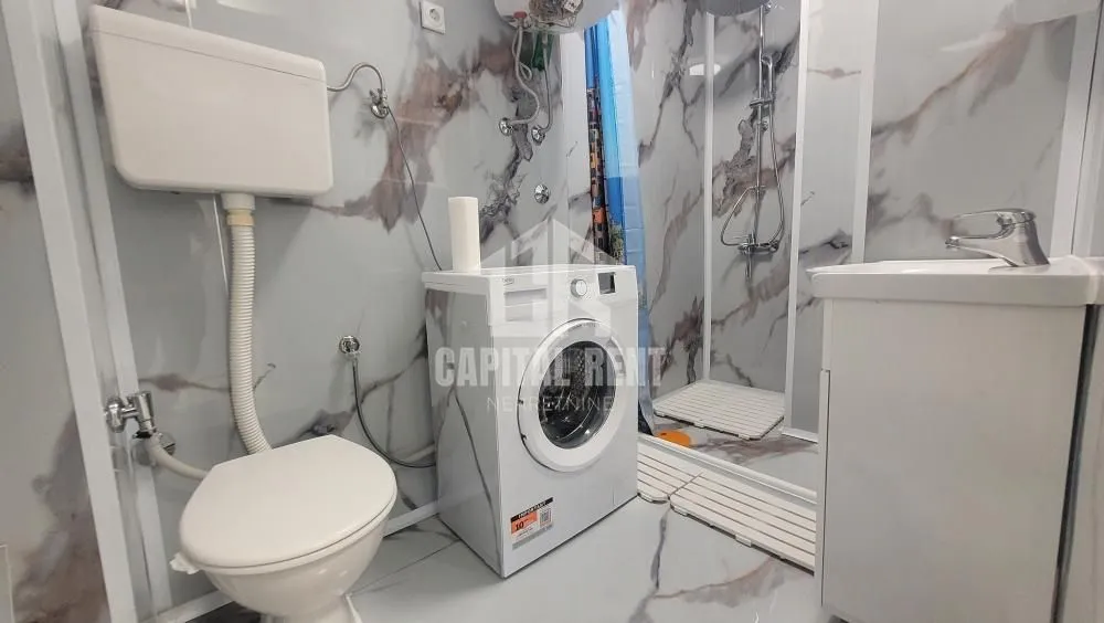 Manje kupatilo sa tuš kabinom, wc šoljom, umivaonikom i veš mašinom.