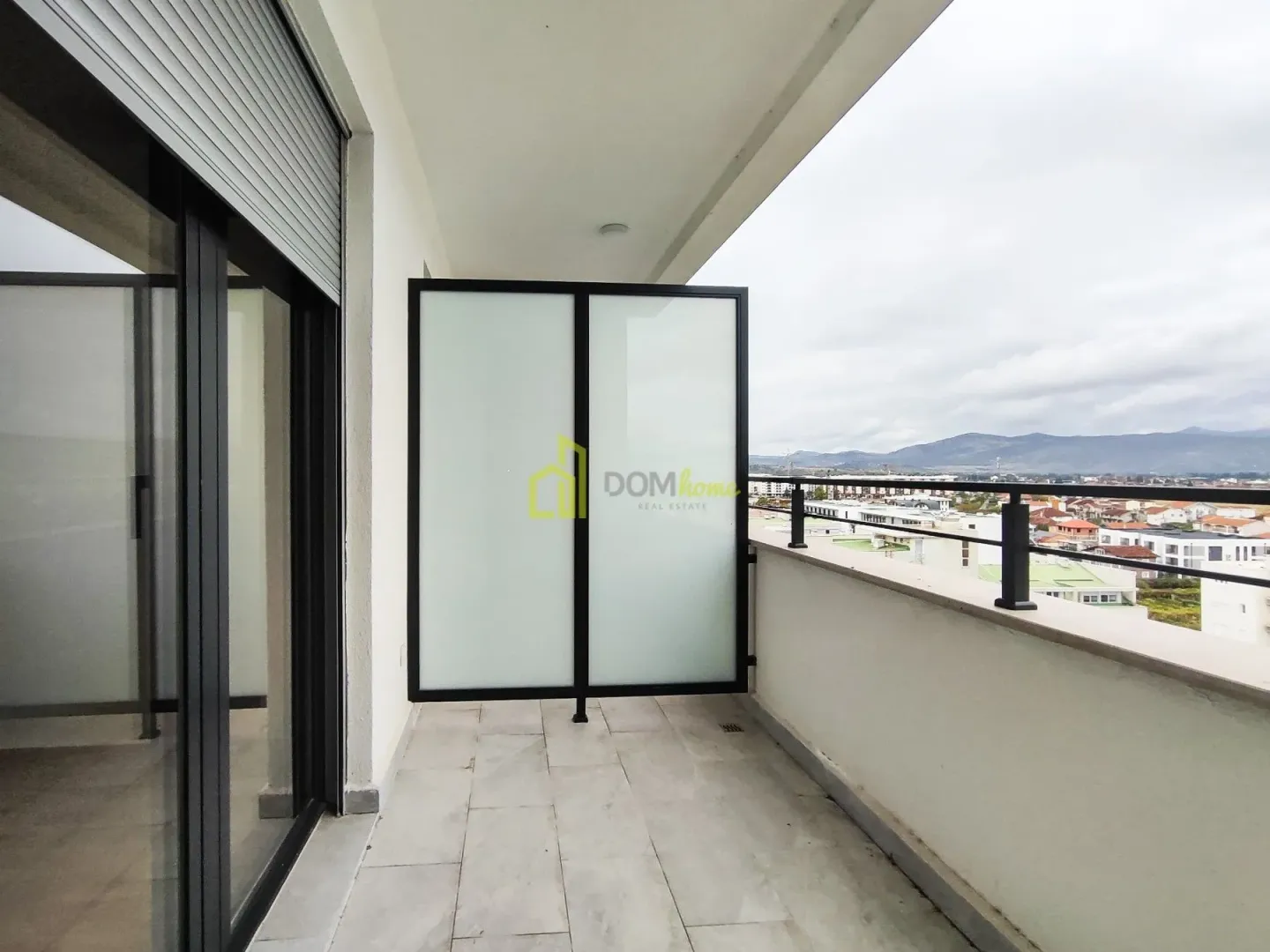 Covered balcony with tiled flooring and a view of the neighborhood and surrounding hills.
