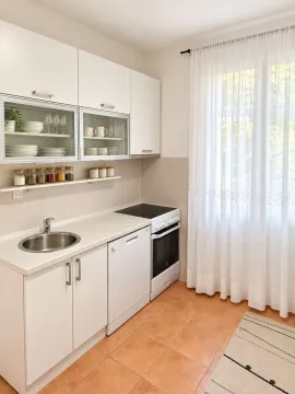 Bright kitchen with white cabinets and a window with a curtain. - image 3