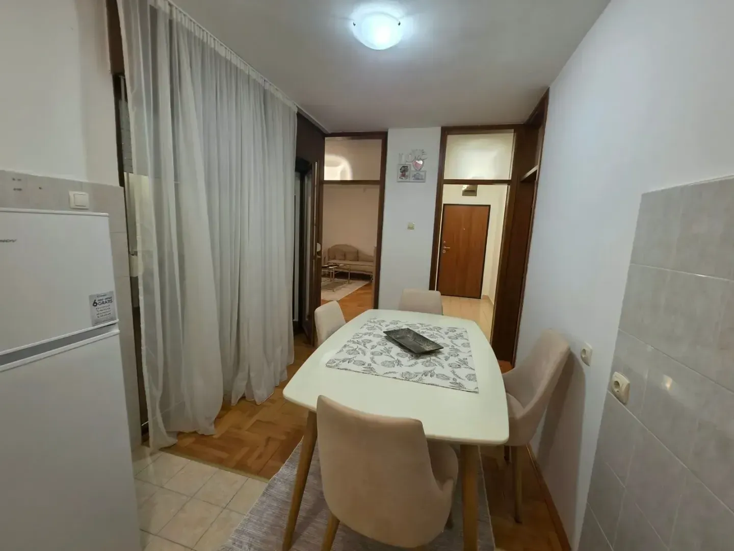 Trpezarija sa stolom i stolicama, povezana sa kuhinjom.
