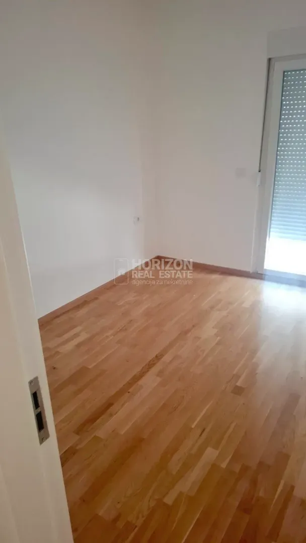 Empty room with parquet flooring and balcony doors.