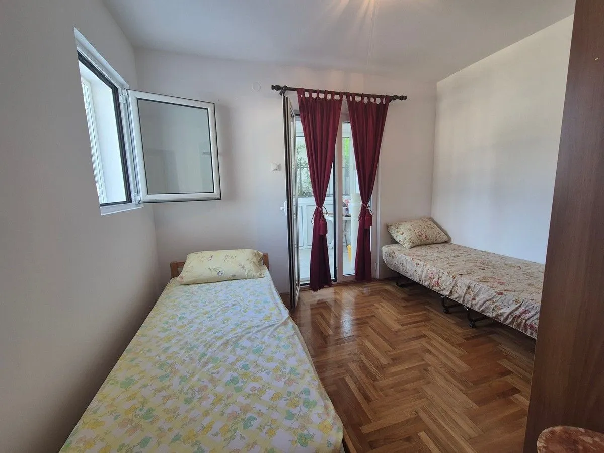 Bedroom with two single beds, wooden flooring, and balcony access.