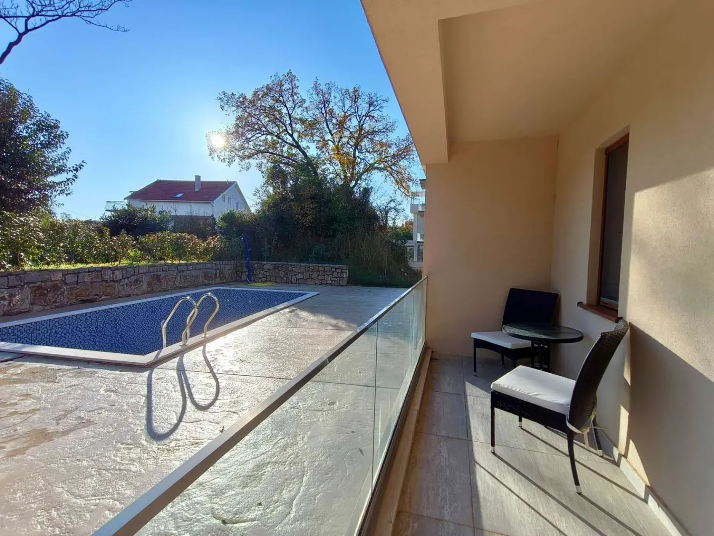 Covered terrace with seating furniture and a view of the pool and yard.