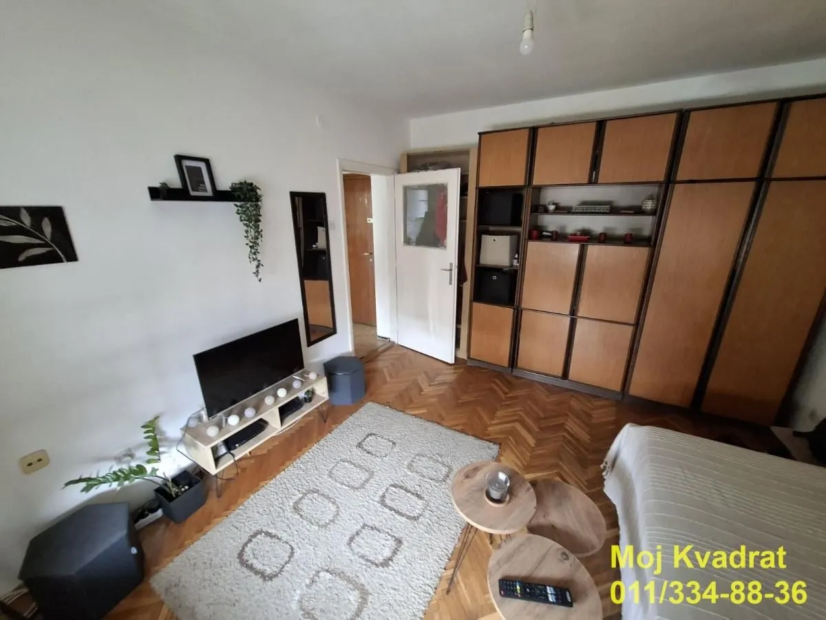 Living room with a seating arrangement, TV and wooden cabinets.