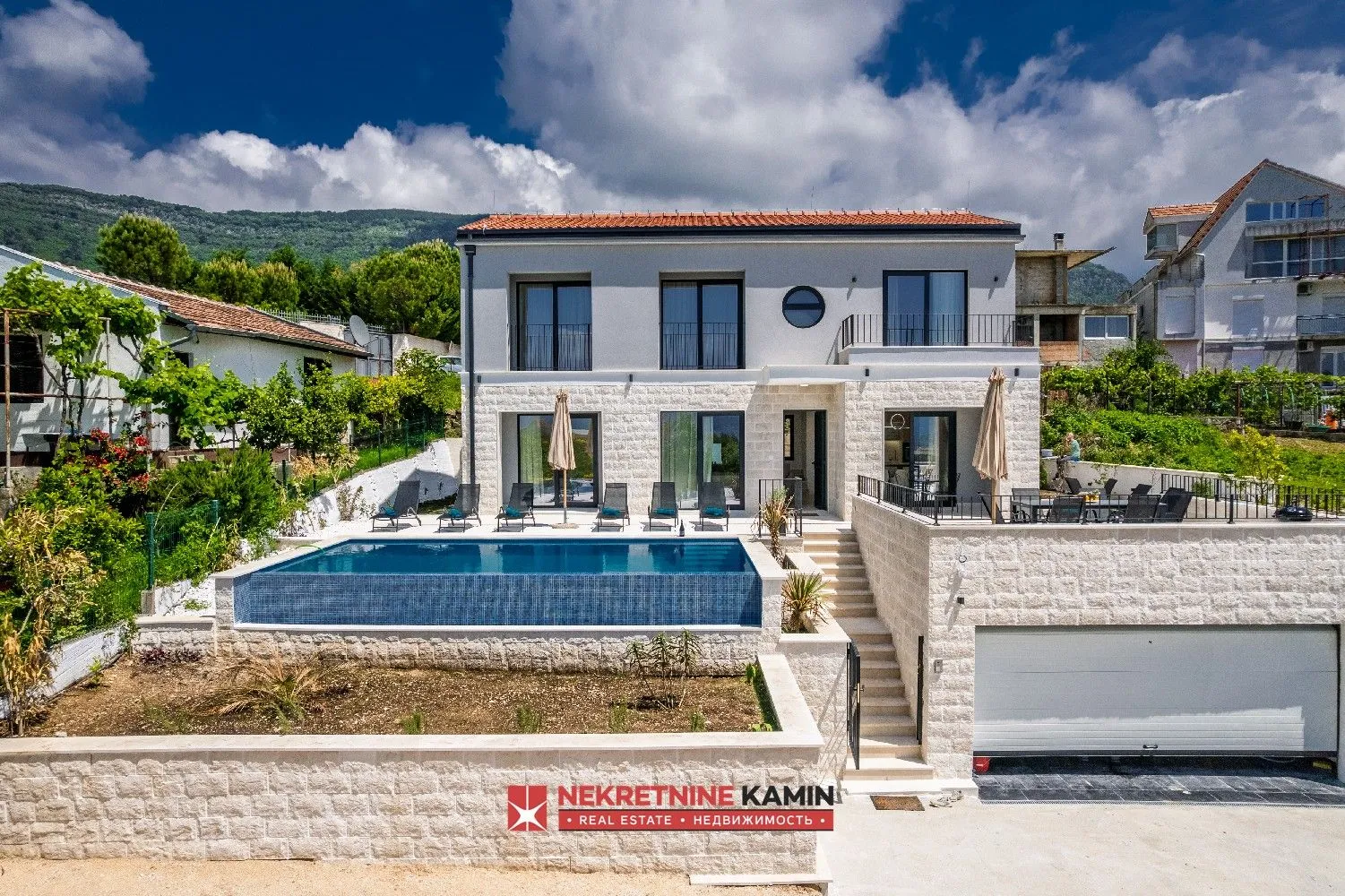 Pogled na dvospratnu kuću sa bazenom i garažom.