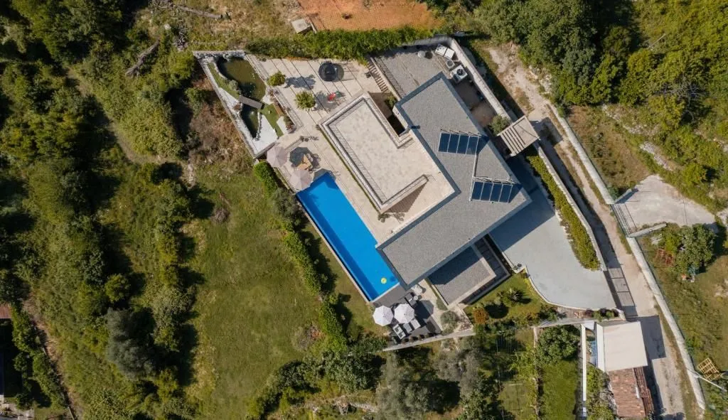 Pogled iz vazduha na kuću sa bazenom i uređenim dvorištem.