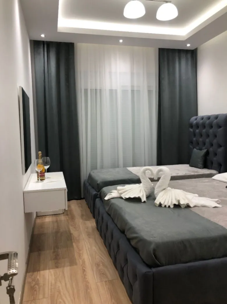 Modern bedroom with two beds and decorative towels.