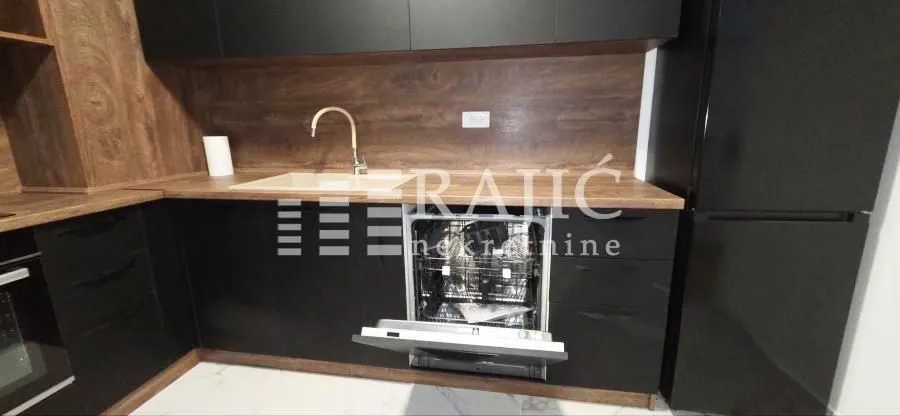 Modern kitchen with dark cabinetry and an open dishwasher.